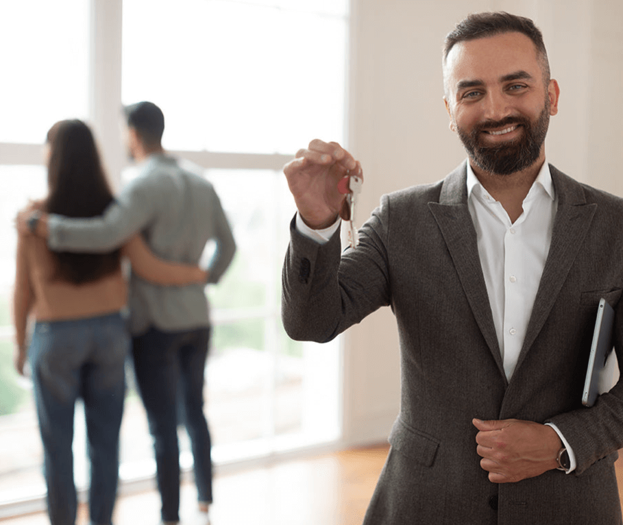 Real estate agent holding keys with happy couple in new home.