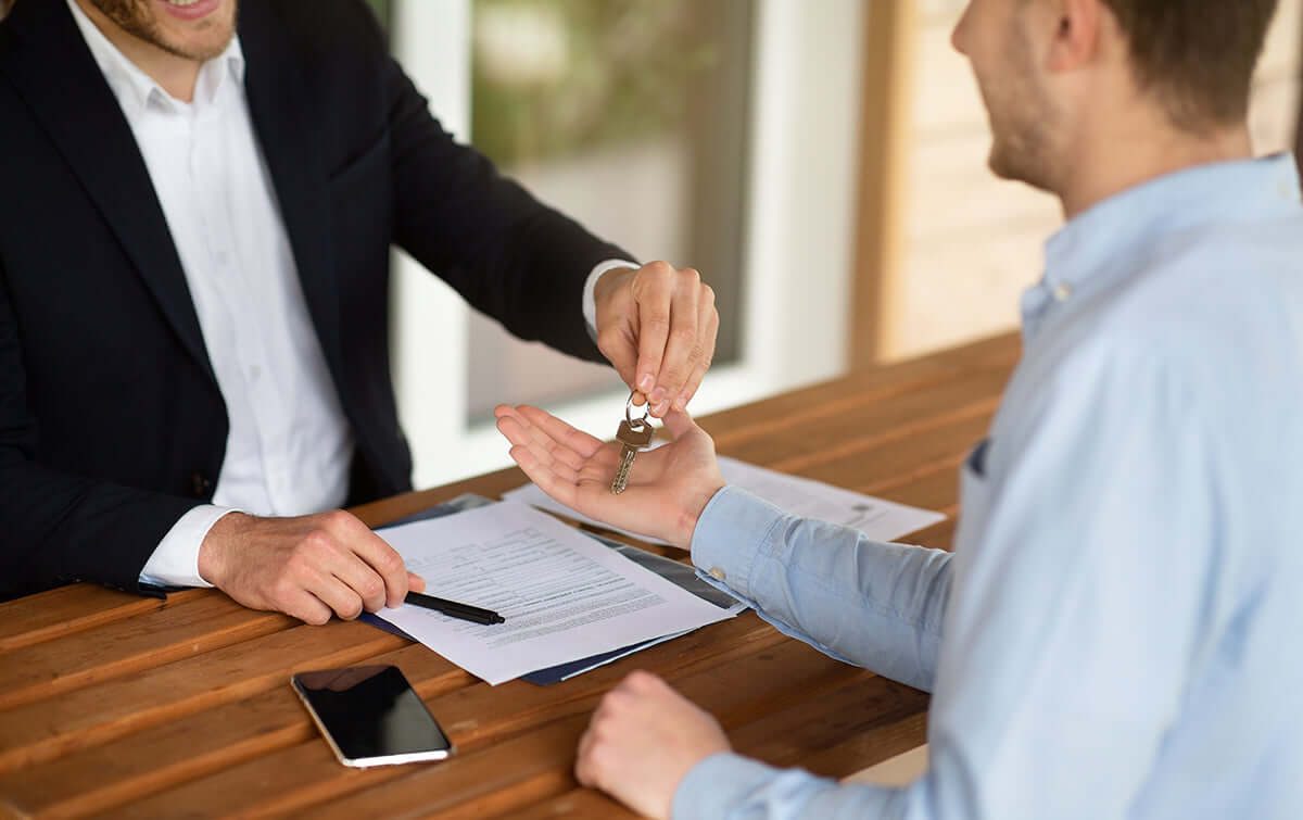 Real estate agent handing keys to a new homeowner signing documents